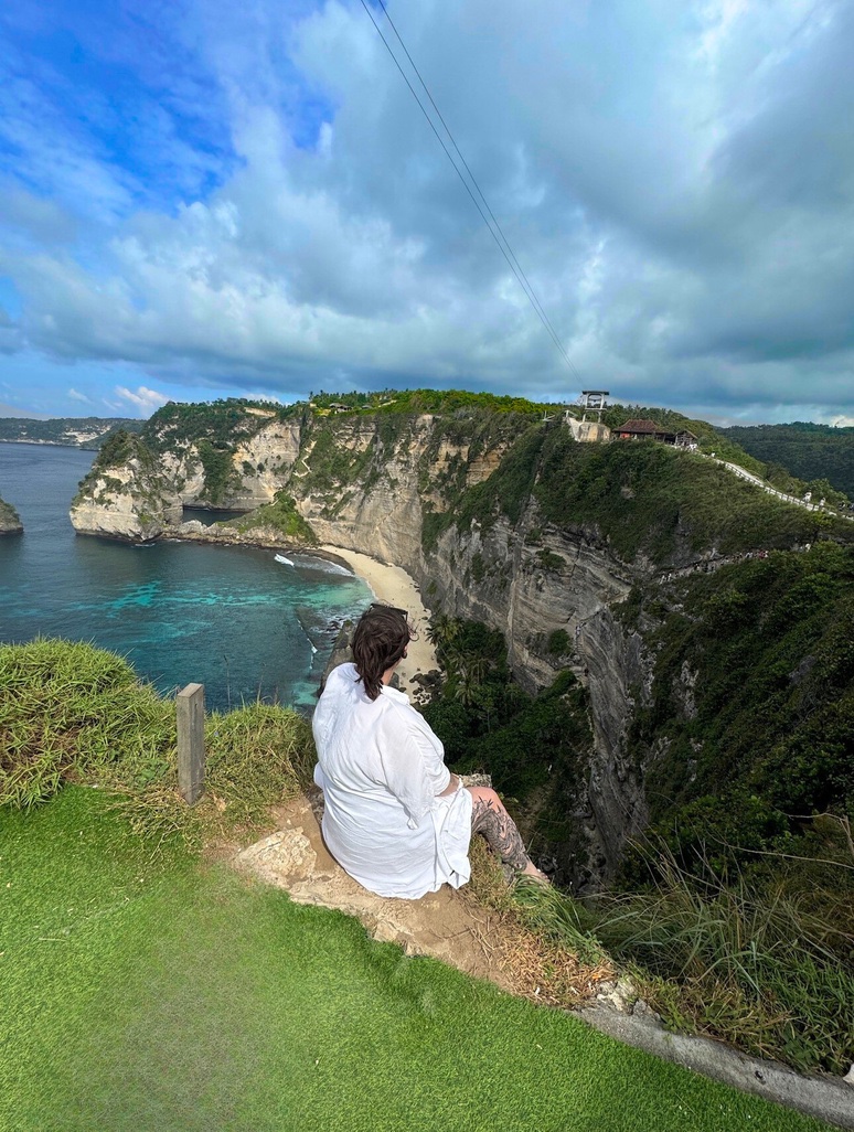 Emily sitting on a clifftop above the ocean in Bali